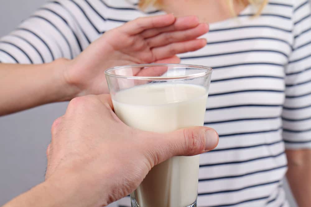 女性伸手阻挡递来的牛奶